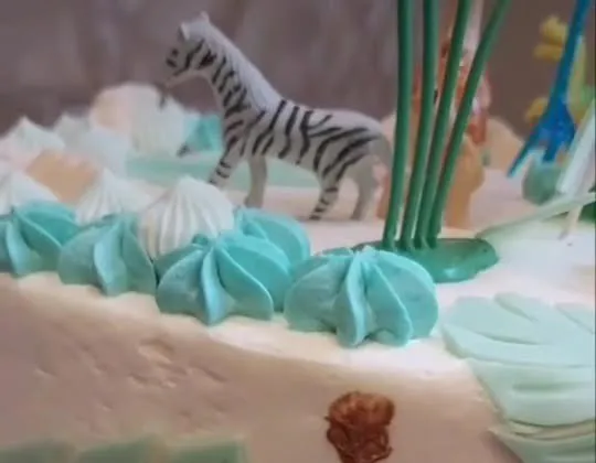 Tortes augšpuse tuvplānā: zebras figūriņa un tirkīza krēma rozetes